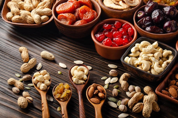 Semillas de nueces y frutos secos en tazones y cucharas en la mesa de la cocina de madera