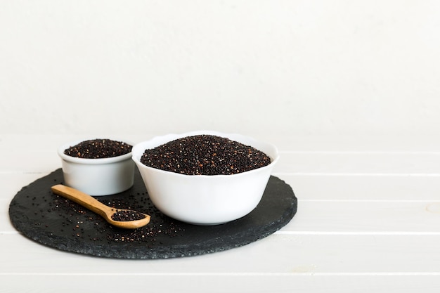 Semillas de quinua en un tazón y cuchara sobre fondo de color Kinwa saludable en un tazón pequeño Superalimento saludable