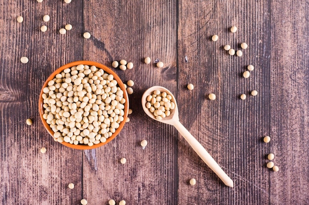 Semillas de soja crudas en una cuchara y un frasco sobre la mesa Fuente de proteína vegetal Vista superior