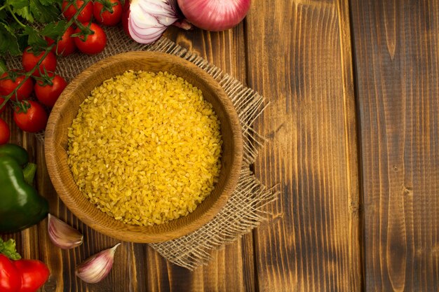 Foto sêmolas de bulgur na tigela marrom e vegetais