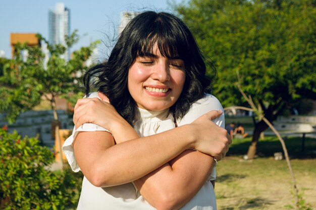 Sempre ama-se a si mesma antes de tudo. Jovem mulher latina a abraçar-se.