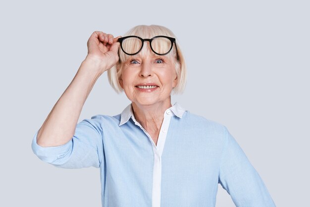 Sempre confiante. Linda mulher sênior ajustando os óculos e sorrindo