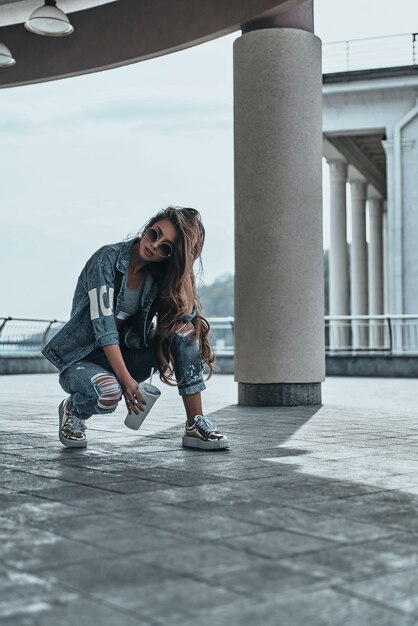 sempre em grande estilo. Mulher jovem e bonita em jeans mantendo a mão no cabelo