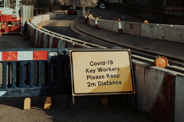 Señal de advertencia de distanciamiento físico para los trabajadores de la construcción de carreteras durante la pandemia de covid-19