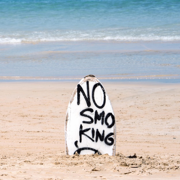 Señal de advertencia de no fumar en la tabla de surf blanca en la playa en verano concepto de diseño de protección ambiental del mar espacio de copia estilo de vida