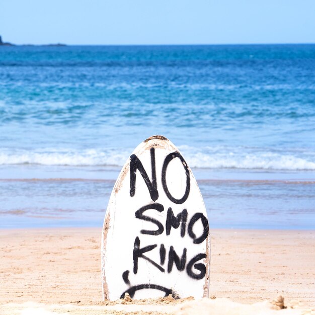 Señal de advertencia de no fumar en la tabla de surf blanca en la playa en verano concepto de diseño de protección ambiental del mar espacio de copia estilo de vida