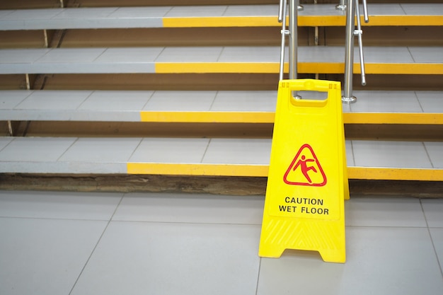 Señal de advertencia con texto ruso precaución piso mojado. Un letrero cerca de los escalones en el centro comercial