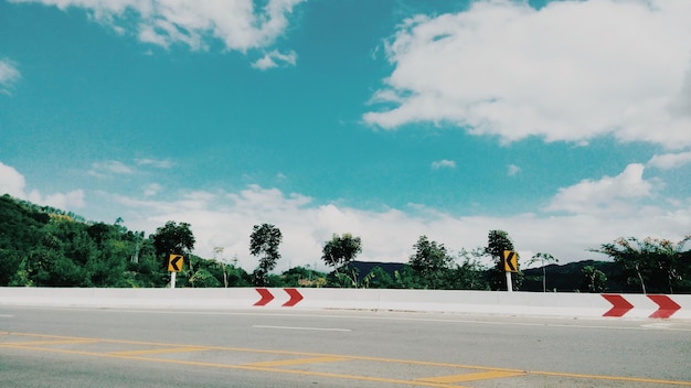 Señal de carretera por árboles contra el cielo en la ciudad