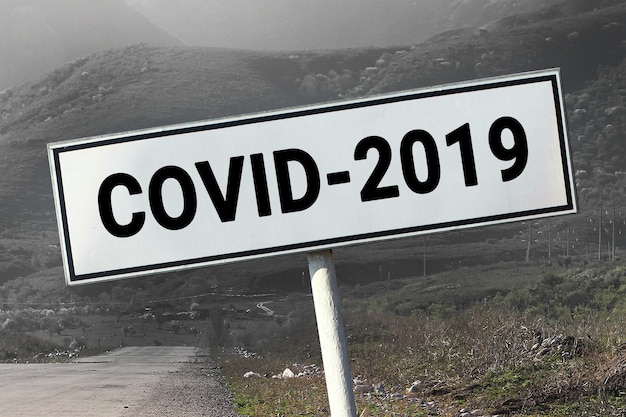 Señal de carretera y carretera con palabra - Covid-2019. Concepto de coronavirus de viajes de peligro.