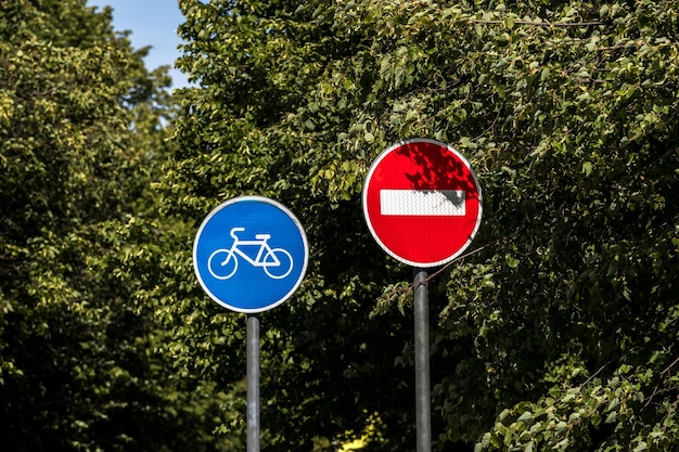 Señal de carretera de carril bici y señal de prohibición de tráfico en el fondo de hojas de árbol verde