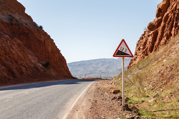 Señal de carretera cuesta abajo con porcentaje en una carretera de montaña, señal de advertencia de tráfico de Kirguistán