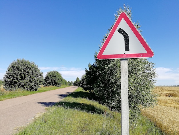 Señal de carretera de un peligroso giro en verano en un día claro y soleado