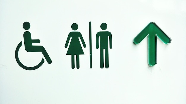 Señal de dirección de baños públicos contra un fondo blanco