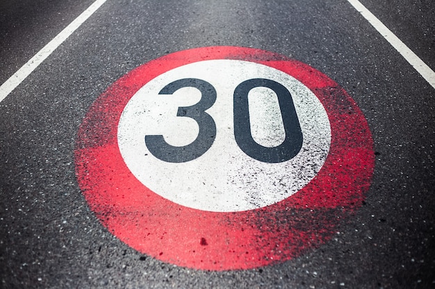 Señal de límite de velocidad de 30 km / h pintada en carretera asfaltada.