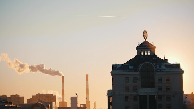 Señal de metro al atardecer en la parte superior de la chimenea de la industria de la construcción en el fondo