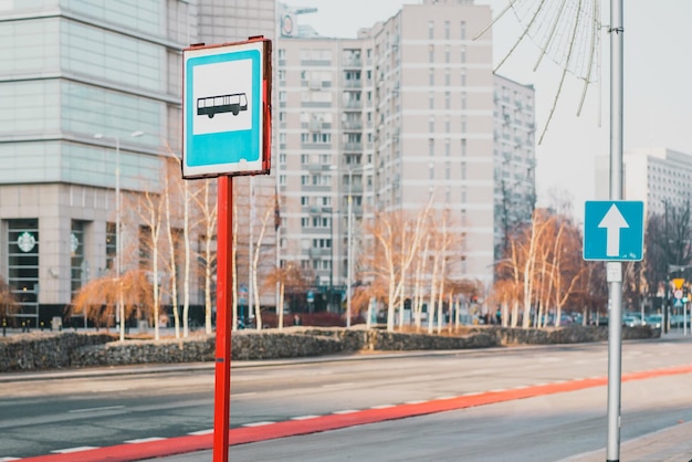 Señal de parada de autobús cerca de la parada de autobús en la ciudad Señal azul Siga recto Flecha blanca Centro Distrito financiero Rascacielos urbanos al aire libre Carretera vacía