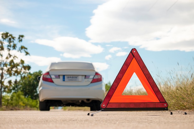 Señal de paro de emergencia y coche roto en carretera.