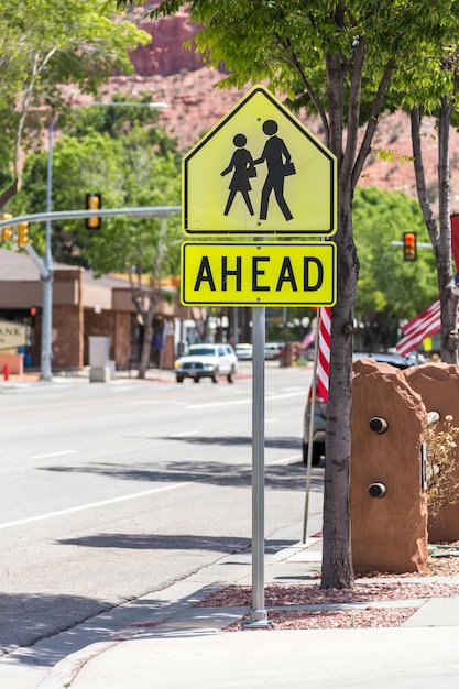 Señal de paso de peatones contra árboles verdes en una pequeña ciudad americana