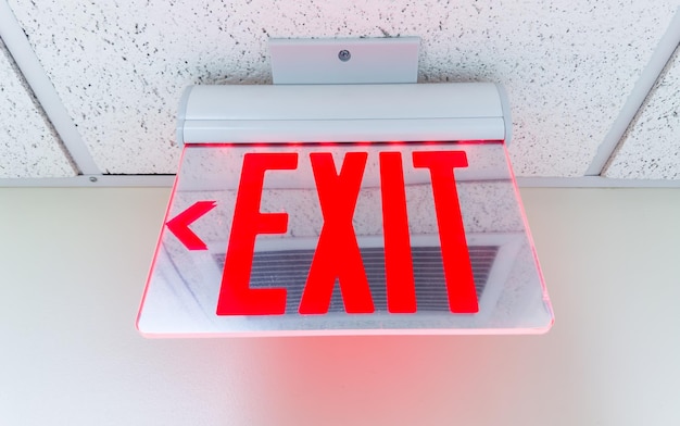 Foto señal de salida contra un fondo oscuro que simboliza la seguridad y el escape con letras verdes y flecha con