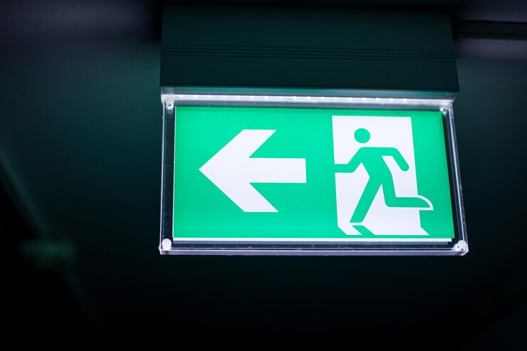 Foto la señal de salida verde y blanca cuelga del techo del pasillo iluminada en la oscuridad