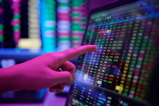 Señalando con el dedo los datos del mercado de valores en el monitor