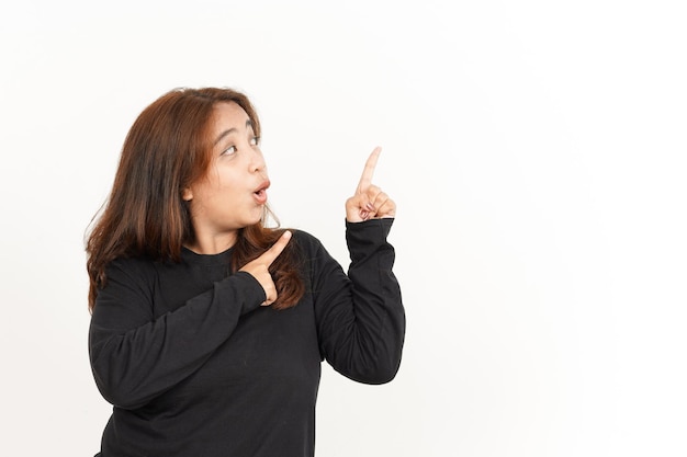 Señalando a un lado de la hermosa mujer asiática vistiendo camisa negra aislado sobre fondo blanco.