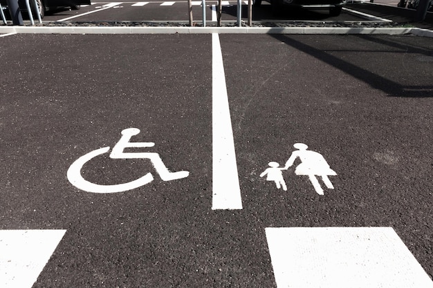 Foto señales de estacionamiento para discapacitados y madres con niños sobre asfalto