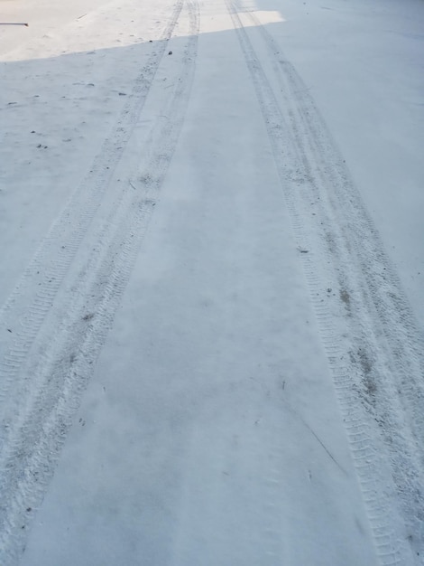 Señales de ruedas de coche de invierno en la carretera de la calle del pueblo