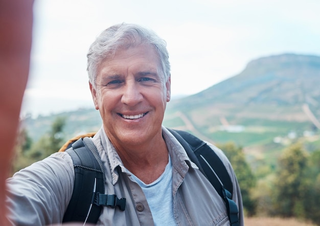 El senderismo es bueno para el alma. Una foto de un anciano tomándose una selfie mientras salía de excursión.