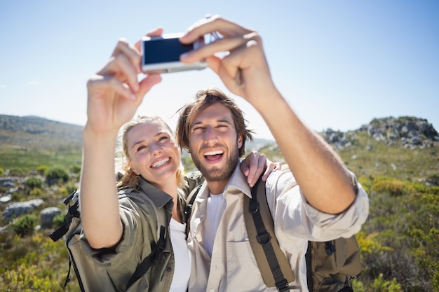 Senderismo pareja de pie en terreno de montaña tomando un selfie