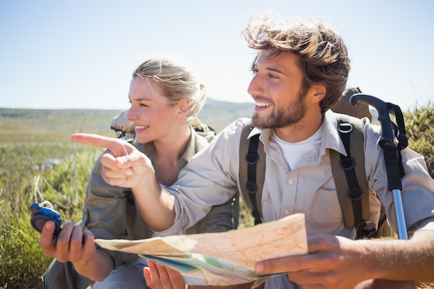 Senderismo pareja tomando un descanso en terreno de montaña con mapa y brújula