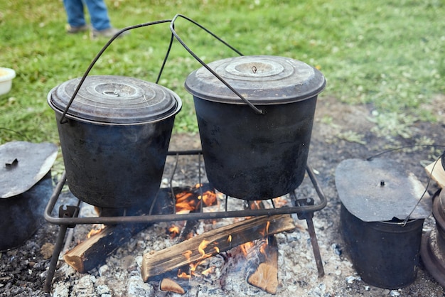 Senderismo pot Bowler en la hoguera en caldero en la hoguera Viajar turismo picnic cocinar cocinar en la hoguera en un caldero fuego y humo