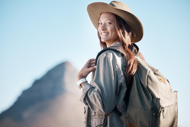 Foto senderismo retrato de mujer y sonrisa en verano en la montaña o explorar con mochila emocionada o feliz por hacer ejercicio chica caminante cielo azul y viajar por la libertad vacaciones en la naturaleza y vacaciones para el objetivo de entrenamiento