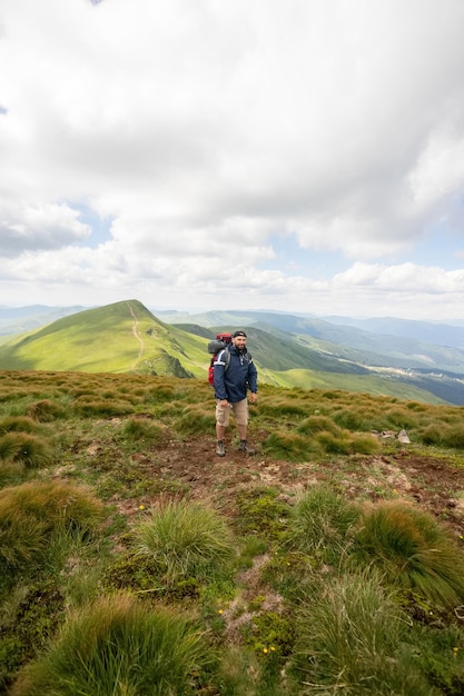 Senderismo solo en las montañas de Noruega Hombre con mochila roja disfrutando del paisaje en el acantilado solo viajando concepto de estilo de vida saludable vacaciones activas de verano