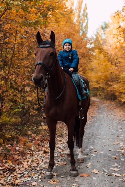 En un sendero del bosque un niño a caballo en otoño