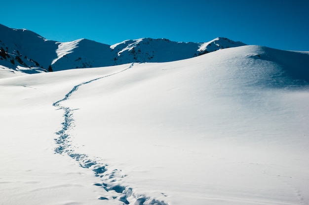 Sendero de ruta en el amanecer de invierno, campo de nieve blanca en el fondo de montañas heladas.