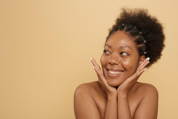 Senhora africana de beleza feliz após tratamento de spa isolado em bege com espaço de cópia Conceito de beleza
