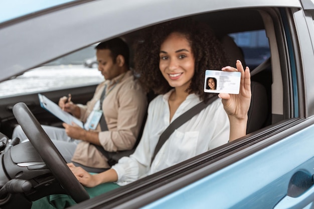 Senhora árabe alegre mostrando cartão de condução através da janela do automóvel