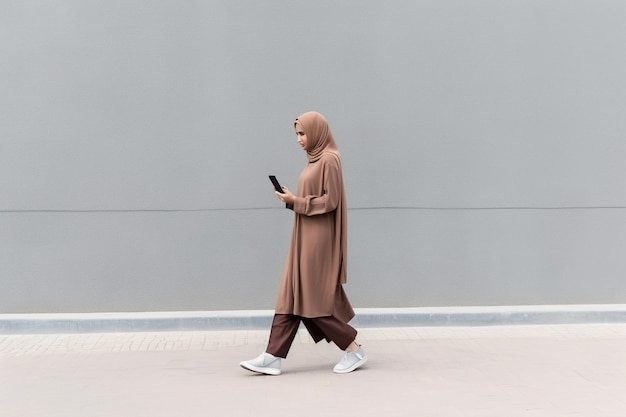 senhora árabe usando celular enquanto caminhava