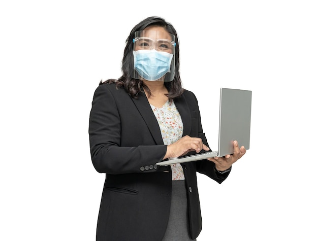 Senhora asiática de negócios usando protetor facial e máscara facial segurando laptop isolado no fundo branco com traçado de recorte.