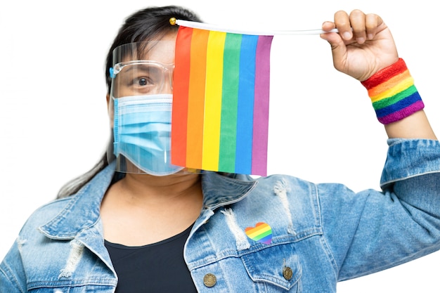 Senhora asiática que veste o revestimento azul de brim que guarda a bandeira da cor do arco-íris, símbolo do mês do orgulho de LGBT.