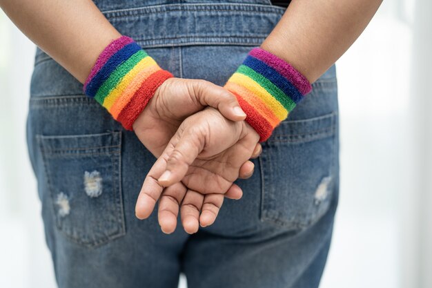 Senhora asiática usando pulseiras com a bandeira do arco-íris, símbolo do mês do orgulho lgbt