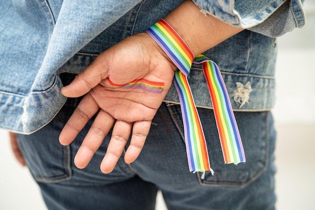 Senhora asiática usando pulseiras de bandeira do arco-íris símbolo do mês do orgulho lgbt celebra anualmente em junho social de direitos humanos de transgêneros gays lésbicas bissexuais