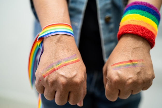 Senhora asiática usando pulseiras de bandeira do arco-íris símbolo do mês do orgulho lgbt celebra anualmente em junho social de direitos humanos de transgêneros gays lésbicas bissexuais
