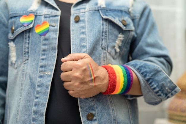 Senhora asiática usando pulseiras de bandeira do arco-íris símbolo do mês do orgulho LGBT celebra anualmente em junho social de direitos humanos de transgêneros gays lésbicas bissexuais