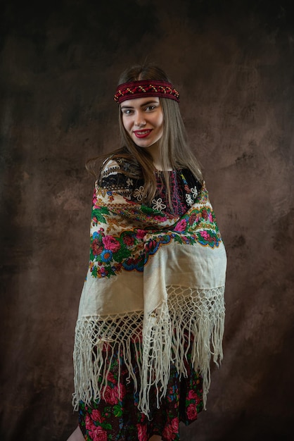 Senhora bonita em roupas nacionais ucranianas com um lenço na cabeça isolado em fundo escuro
