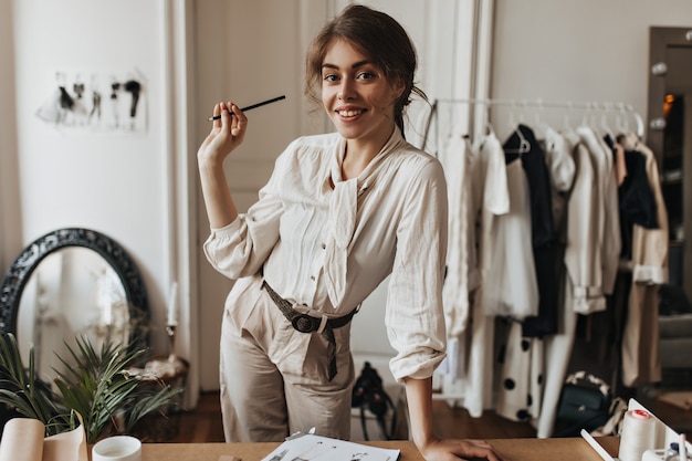 Senhora com roupa bege posa no local de trabalho