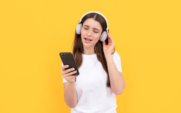 Senhora de camisa branca cantando em fones de ouvido e conversando na tecnologia do telefone