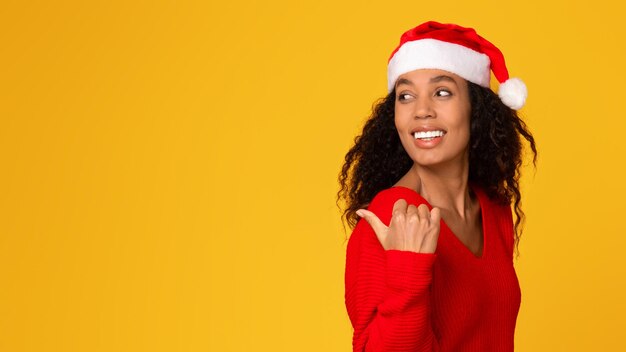 Senhora de chapéu de santa apontando para trás no espaço livre em fundo amarelo