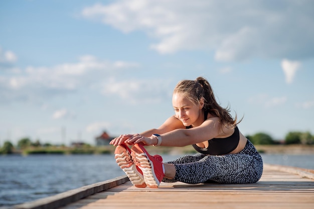 Senhora de fitness em roupas esportivas fazendo exercícios no cais